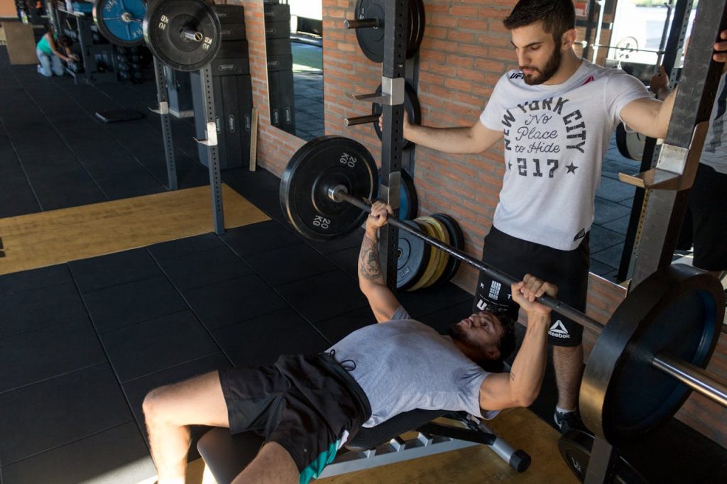 man with personal trainer doing bench press